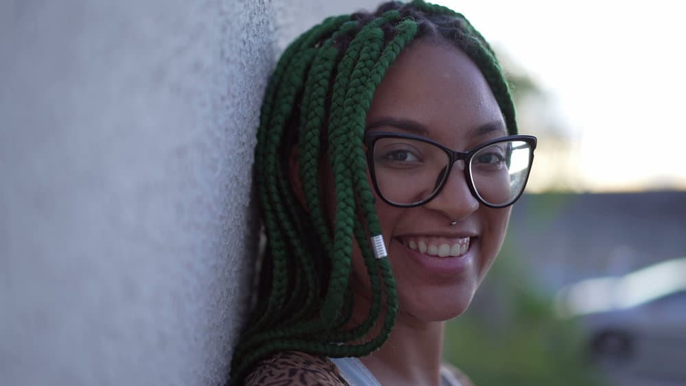 A gorgeous black woman wearing a protective style covering her own hair and scalp with Kanekalon hair.