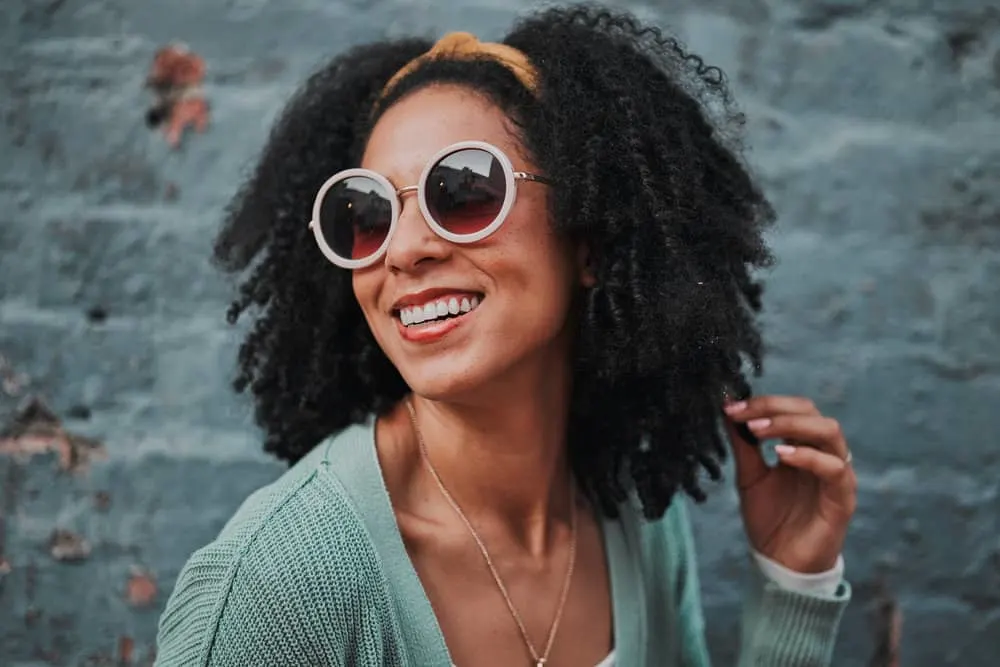 A fashionable black female with dry hair uses the co-wash method to maintain her fine hair strands and oily scalp.