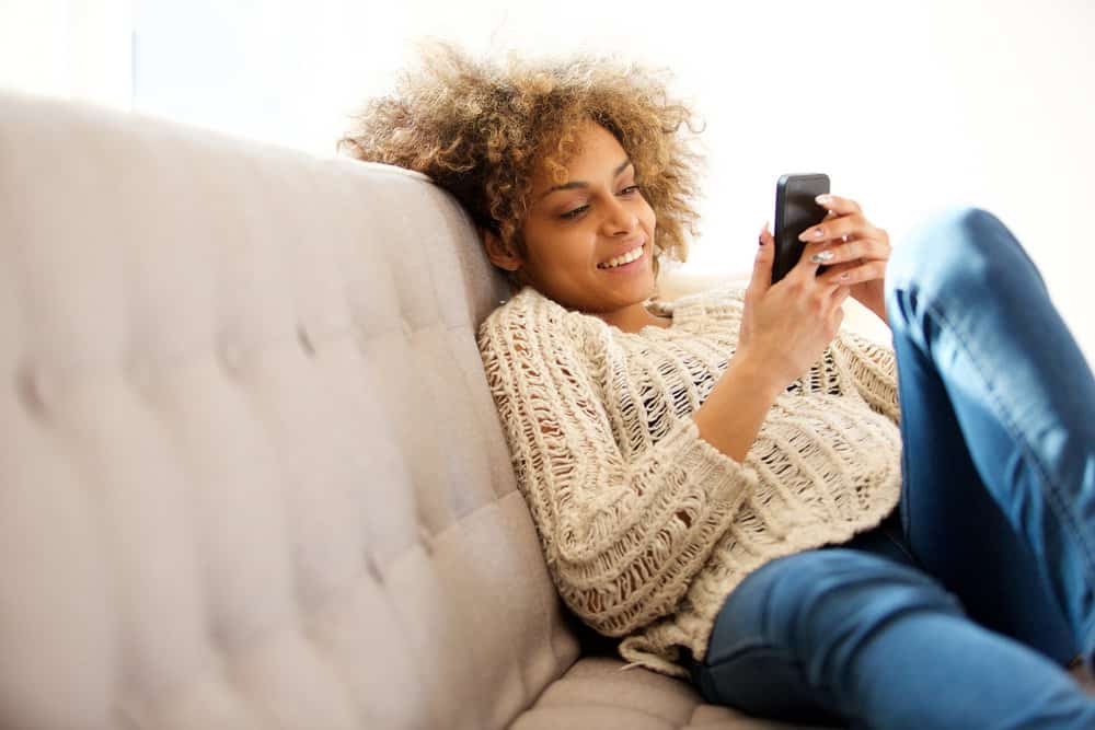 A cute black girl reading an article online about the Crown Act, its significance, and how it will affect students.