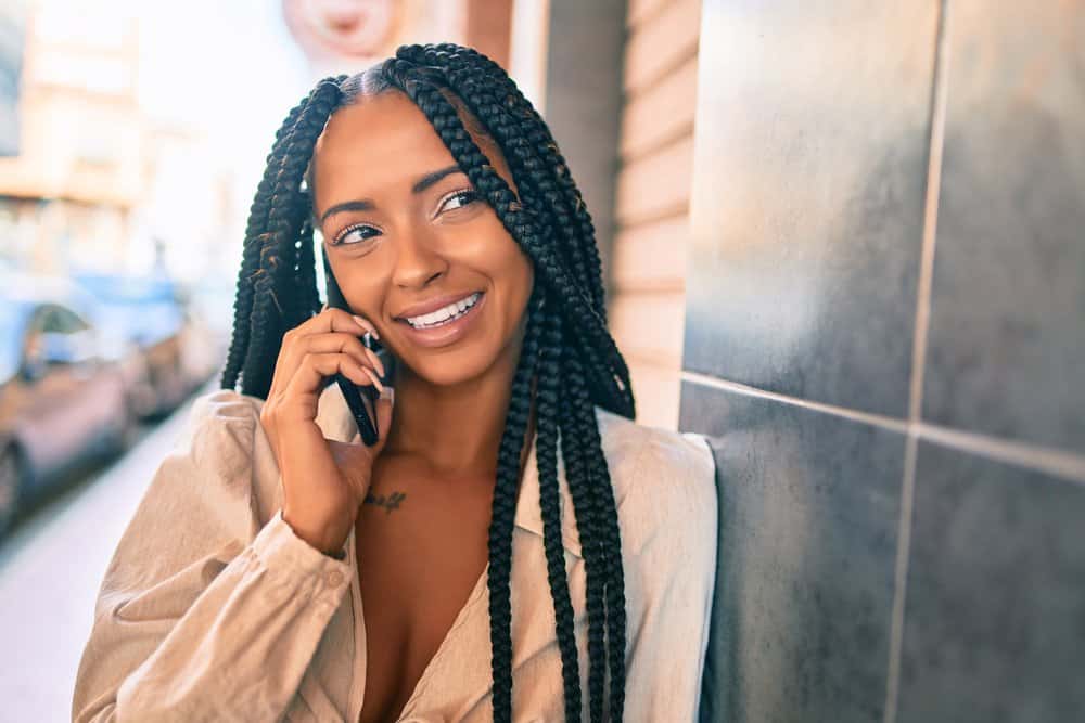 Woman Janet Jackson braids wearing a light brown shirt while talking on an Android phone.