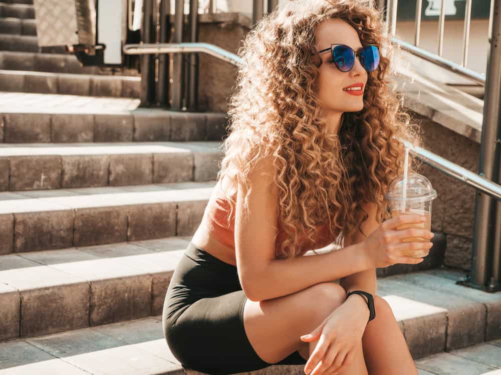 A girl with the perfect shade of blonde and brown curls toned with a liquid from toner after bleaching strands.