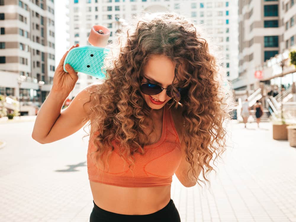 A Caucasian female with brown and platinum curls used Wella color charm and purple shampoo to bid brassy goodbye.