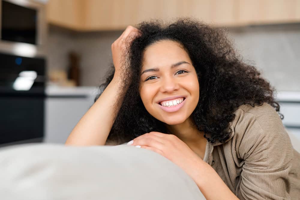 A beautiful serene African-American young woman with very narrow teeth after detangling natural hair strands.