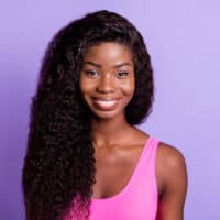 A cute black female wearing a 4x4 lace closure wig with curly hair strands and a natural and beautiful hairline.