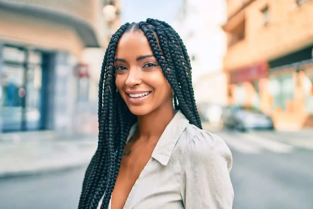 A cute black woman wearing a simple style with black and brown braids that lay close to her scalp.