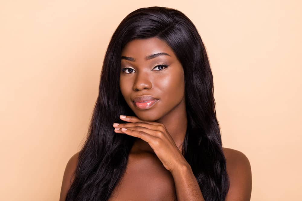 A cute young African American female wearing a curly hair wig with type 3 natural hair density on a lace wig cap.