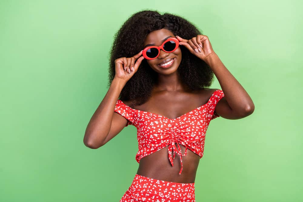 An African female wearing a lace wig with thick hair follicles has a shoulder hair length and natural appearance.