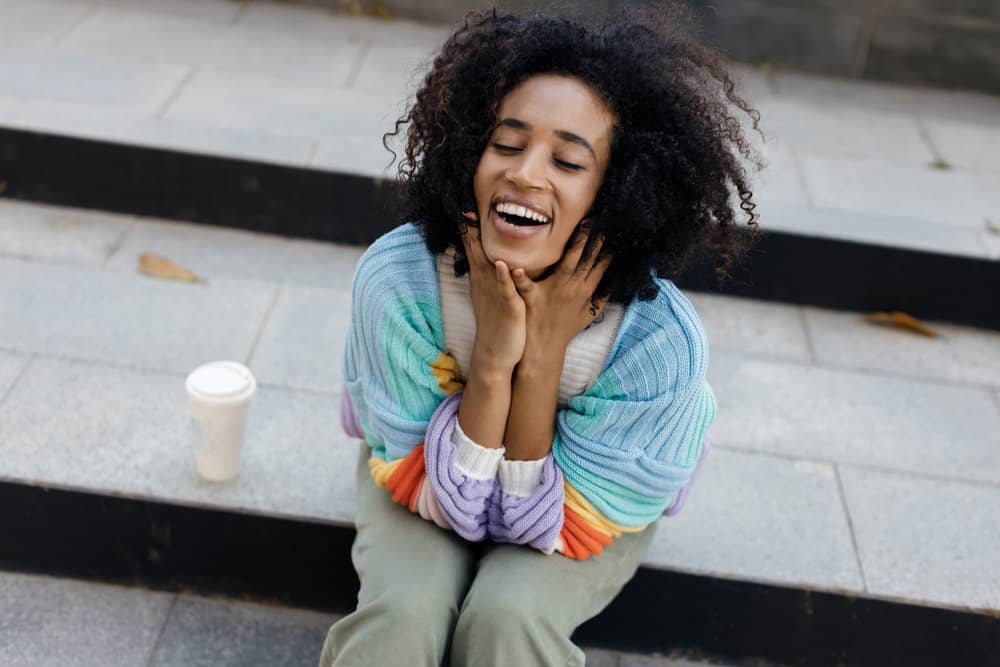 A cute young African American female with slightly wet hair and dead skin on her scalp enjoying a sunny day.