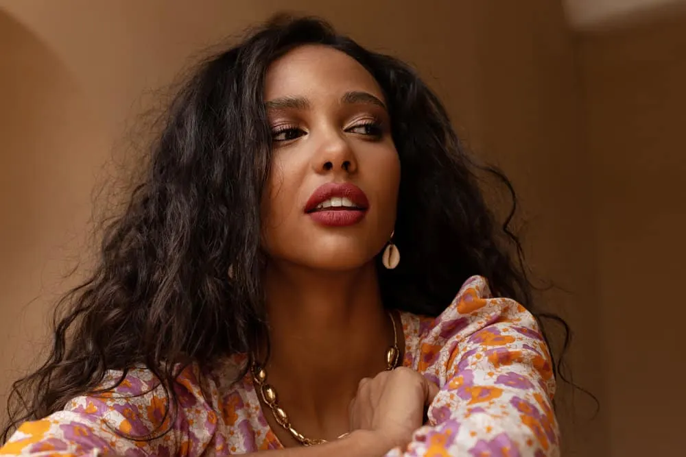 Ayurvedic Hair Growth: How to Use Ayurveda Hair Oil & Herbs 2 A black girl with soft brown skin has dry hair strands styled with aloe vera gel, neem oil, and other natural oils.