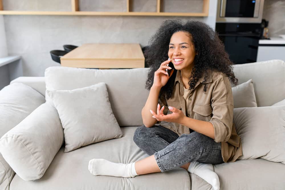 A young multiracial woman talking to a friend about whether aggressive brushing is better on wet or dry hair.