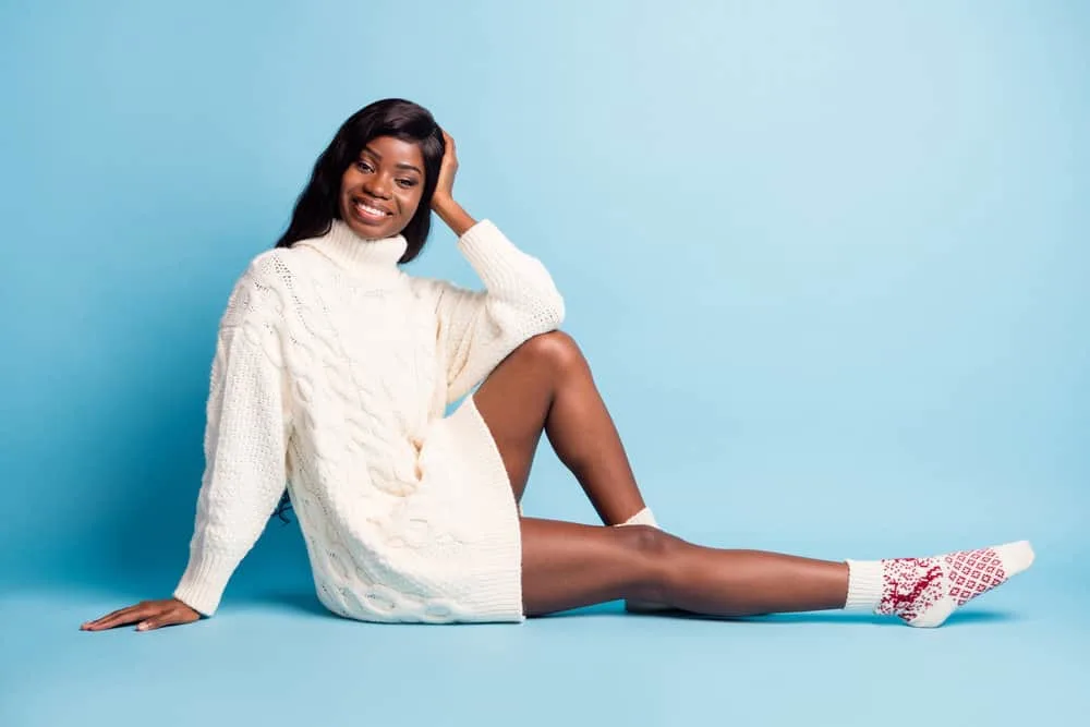 A dark-skinned black girl wearing a high-density wig with a casual white sweater and red and white socks.