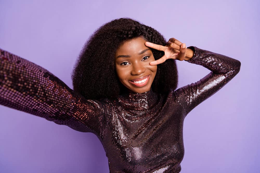 A cute young black lady with her baby hair styled with a toothbrush wearing a half wig with natural parting.