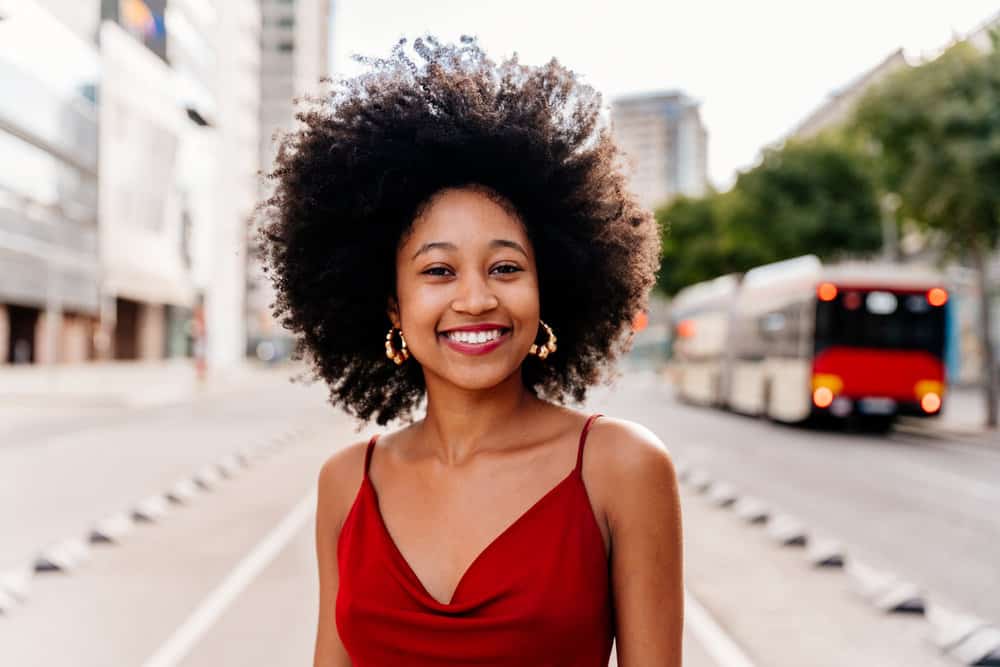 A black woman with low-pH frizzy hair is a wash and go styled created with aloe vera juice and jojoba oil.