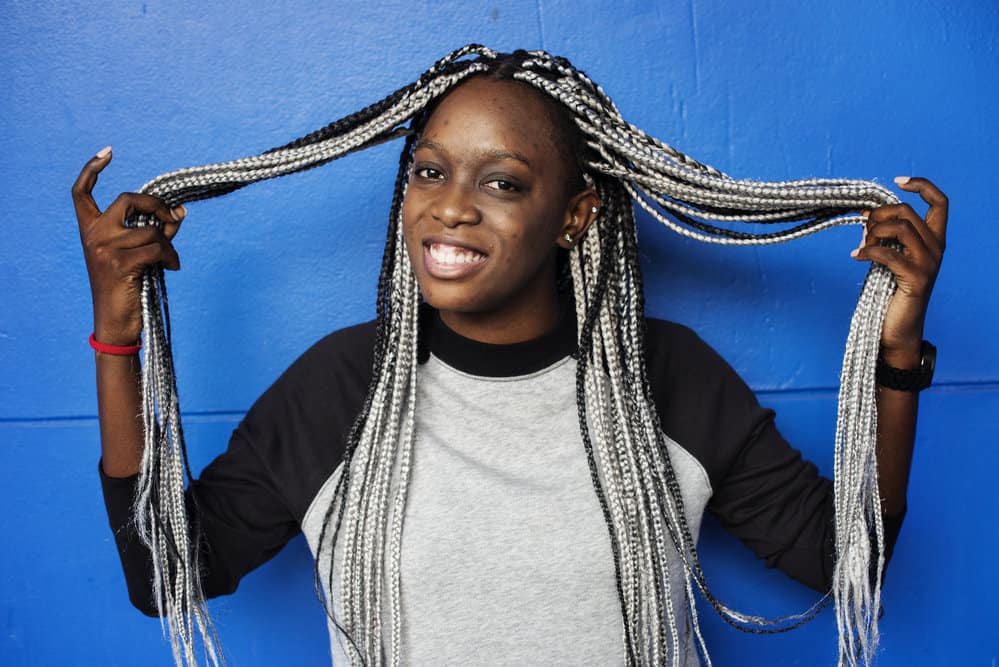 A black girl with black and blonde braiding hair extensions experiencing an allergic reaction from the dirty hair.