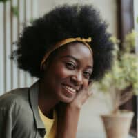 A black lady with natural hair strands has a combo of 4A, 4B, and 4C curly hair types on her loosely packed curls.