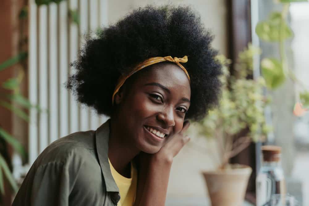 A black lady with natural hair strands has a combo of 4A, 4B, and 4C curly hair types on her loosely packed curls.