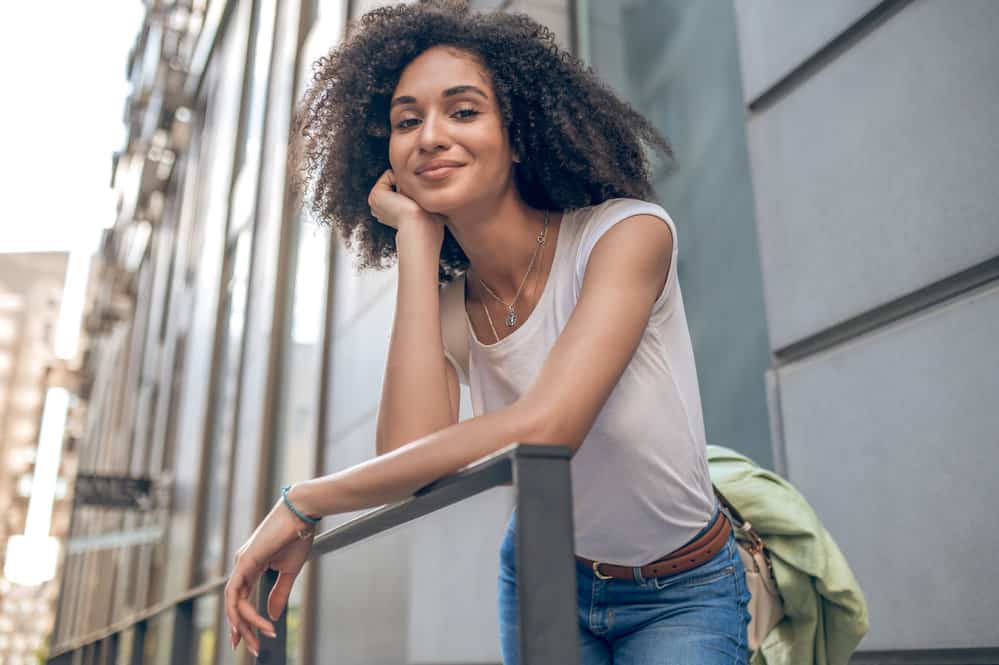 A stylish black girl wearing a white t-shirt has been experiencing hair thinning and poor scalp health.