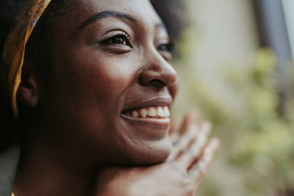 A cute black lady with a 4C curl shape keeps her hair soft and hydrated with essential oils.