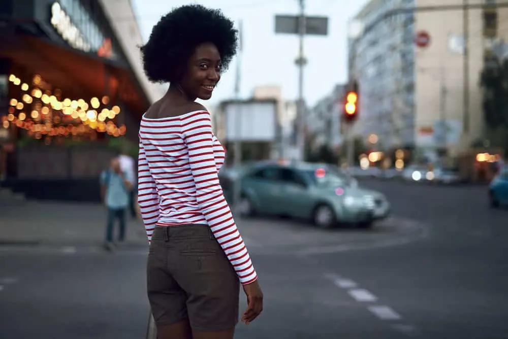Co-washing 4C Hair: How To, How Often, Benefits & Is It Good 8 A fashionable African American female wearing a curly afro styled with castor oil to retain moisture.
