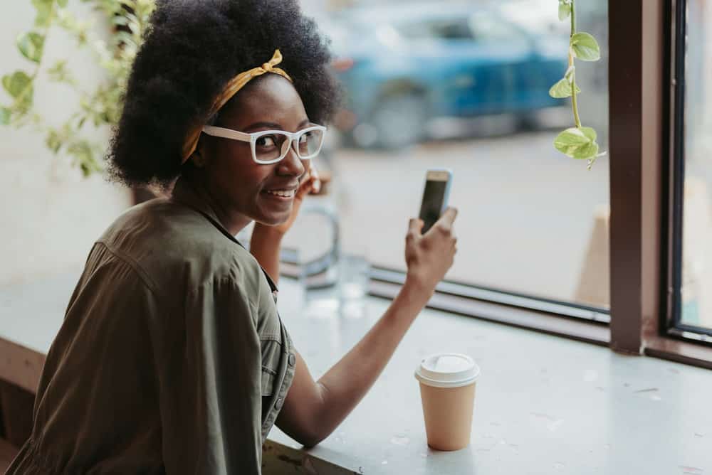 A young American girl in cute eyeglasses wearing a wash-n-go styled with leave-in conditioners and her scalp's natural oils.