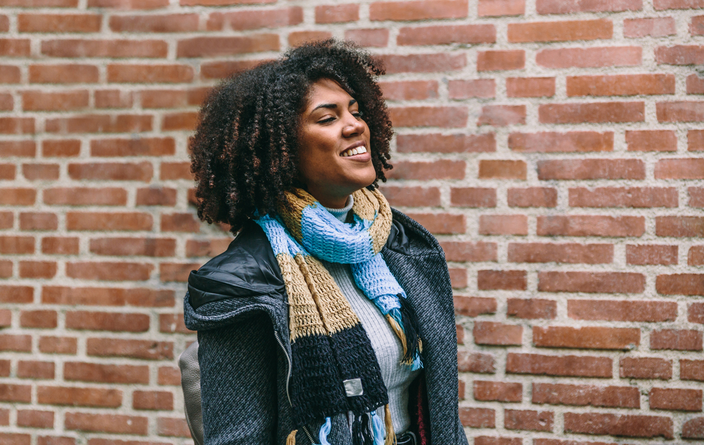 A cute lady with a great smile uses Olaplex for shampoo and conditioner on her natural curls.