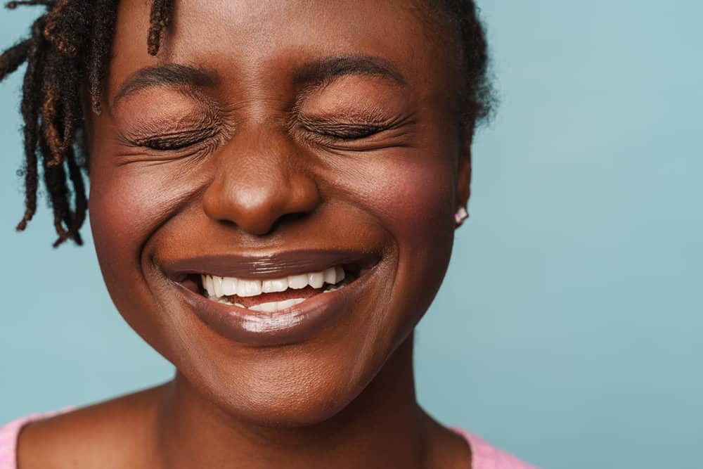 A black female with 4B natural hair showcases her healthy hair styled in instant locs, moisturized with deep conditioners, and palm-rolled for a sleek appearance.