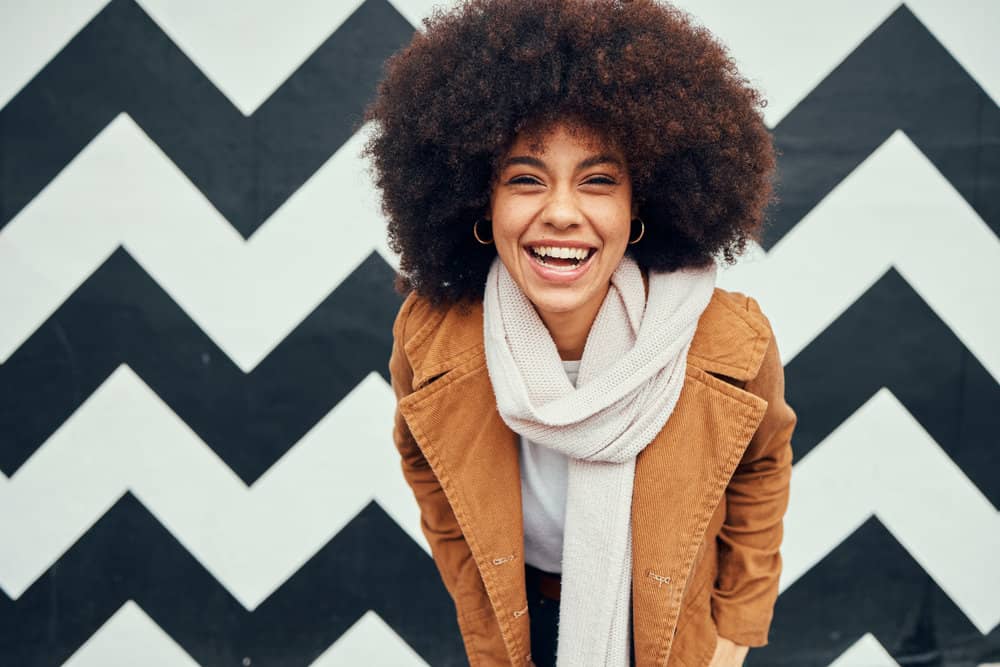 A trendy African American female with fine hair uses a flax gel and collagen peptides on her natural curls.