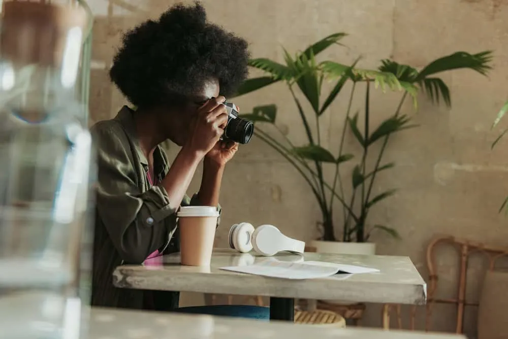 A busy black lady wearing a casual outfit with moisturized hair grows in an afro style due to her 4C strands.