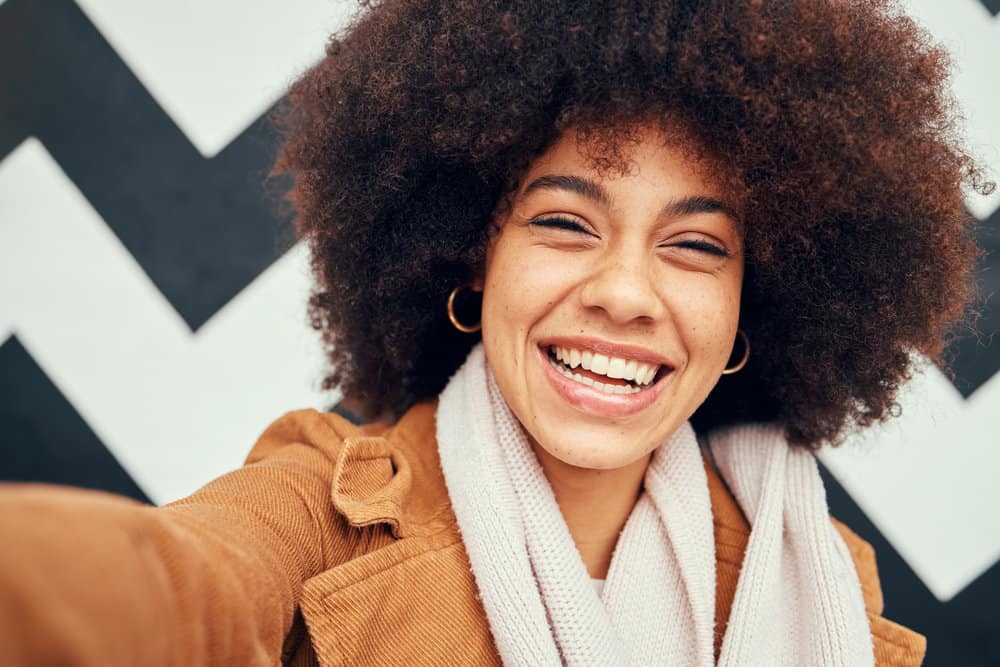 A black female with frizzy curls and wavy hair styled with flaxseed hair gel and coconut oil.