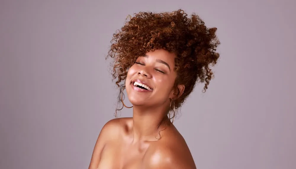 9 Easy Curly Hair Updos: How to Create Curly Updo Hairstyles 16 The black female's naturally wavy hair is styled in an elegant half updo with a French braid and a few loose curls left to frame her face, creating a perfect style for any occasion.