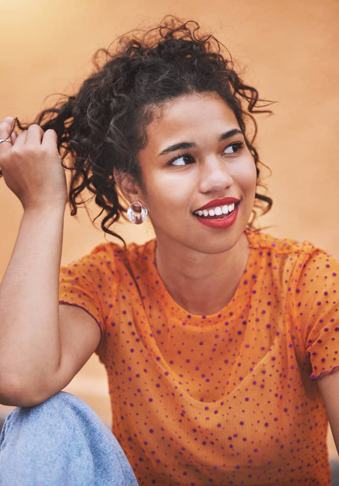 A beautiful mixed-race African American woman with dark hair touching strands of hair with her fingers.