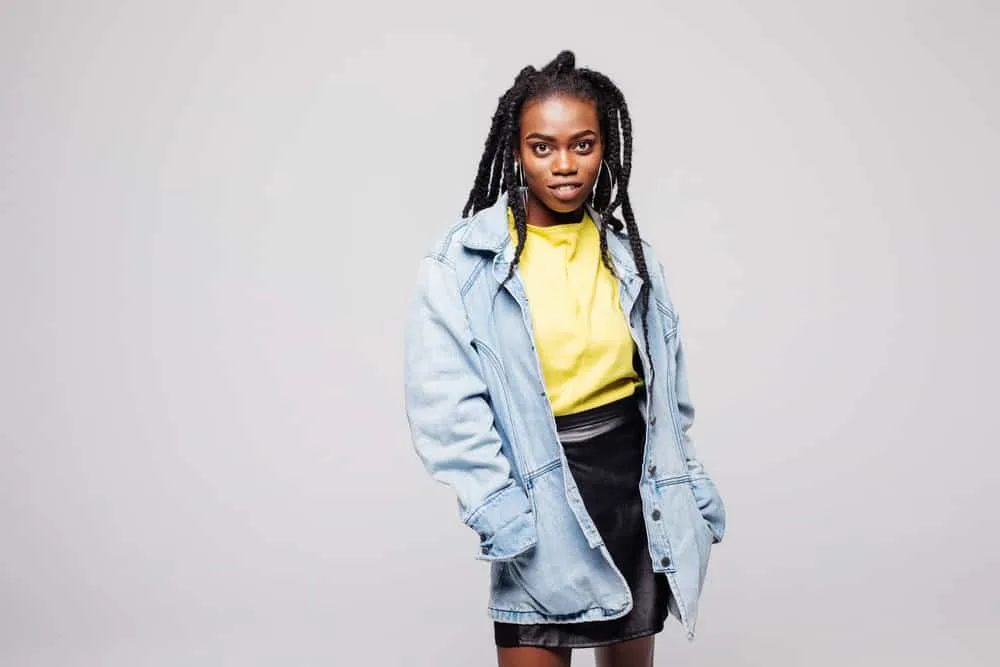 A cheerful black woman wearing multiple French braids created using a tutorial from a celebrity hairstylist.