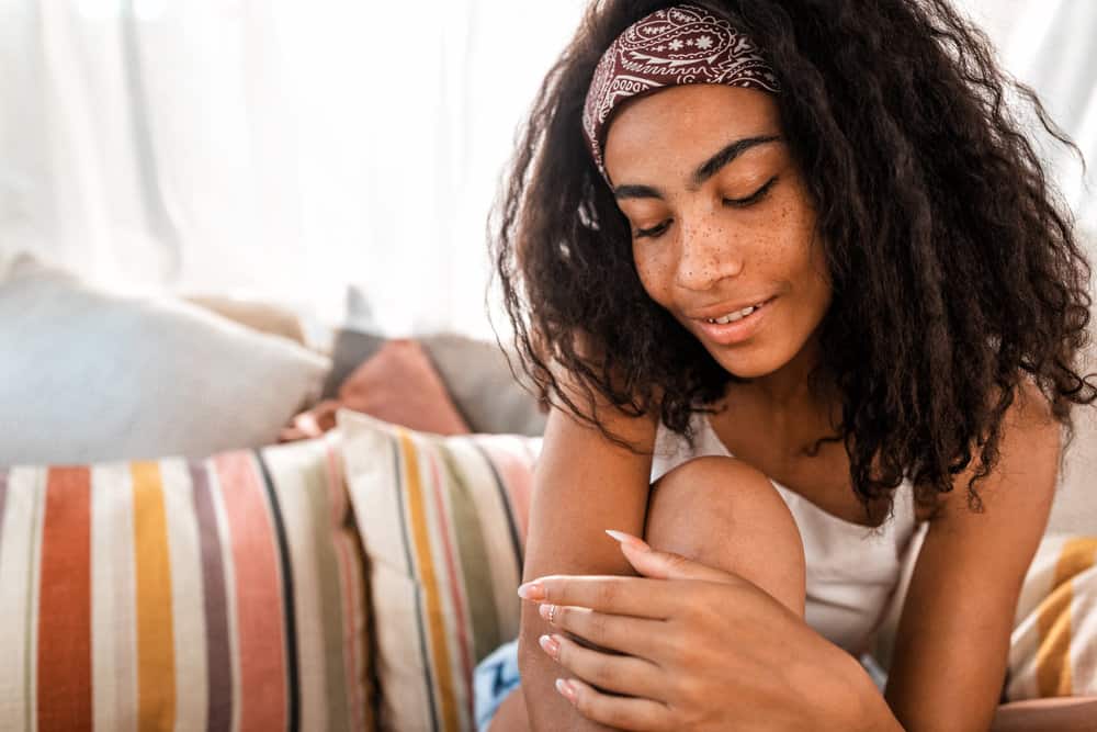 A light-skinned black girl with a type 4 hair type and dark brown hair color with a greenish tint.