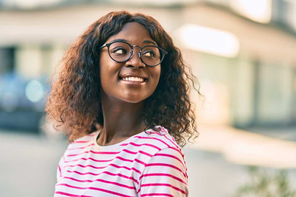 A young dark-skinned African American female is wearing a wig with low-density hair strands.