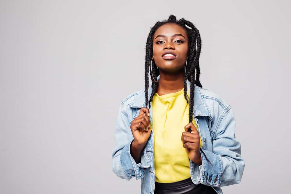 A cute black woman wearing a classic three-strand braid hairstyle created with a rat-tail comb and YouTube tutorial.