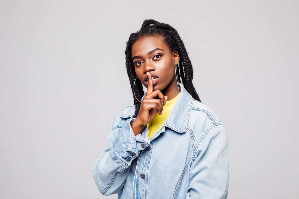 A beautiful dark skin black female wearing a creative double dutch braid hairstyle on her damp hair.