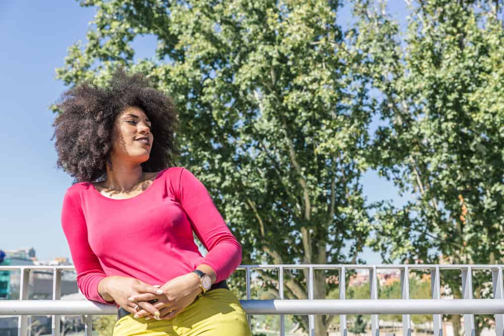 A cute black woman cut her own hair to create side-swept bangs and eliminate split ends.