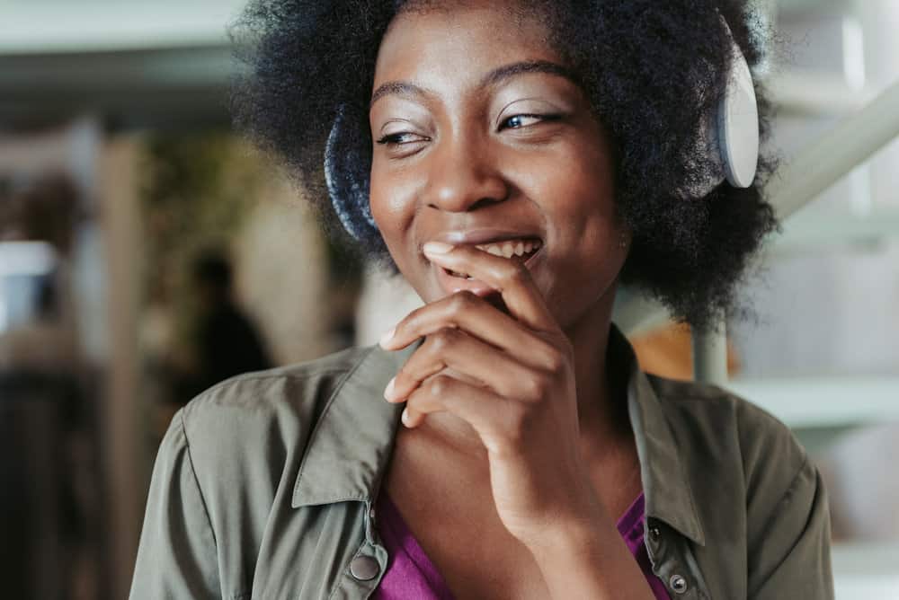 A cute black girl with a tight curl pattern on her 4C natural hair used coconut oil to retain moisture.