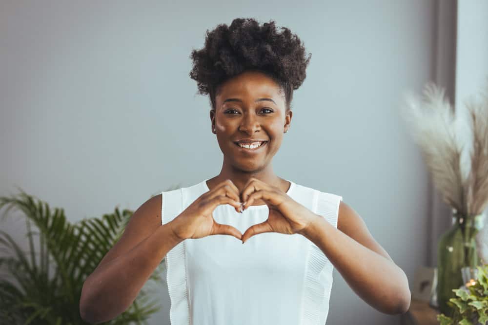 A happy black woman used a deep conditioner on her wet hair to retain as much moisture as possible.