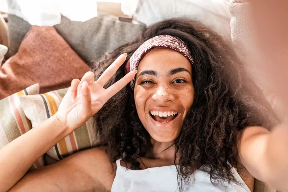 How to Use Clarifying Shampoo on Curly Hair: Step-By-Step 1 A young black lady with color-treated hair strands styled with natural oils and organic styling products.