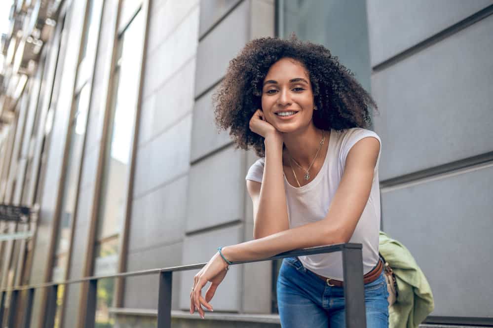 A fashionable black female promotes hair growth with olive oil and other essential oils.