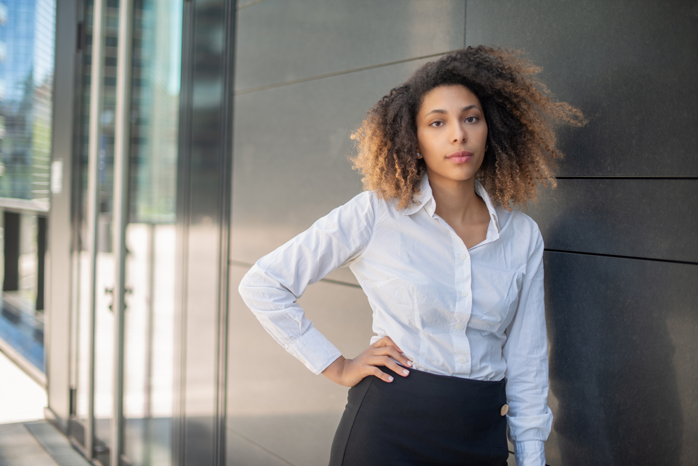 A stylish young black lady with natural curls treated with Shikakai hair oil.