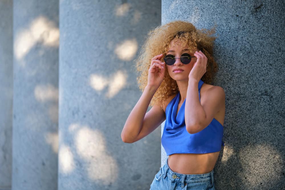 A cute black with a curly hair texture uses an Olaplex treatment to strengthen hair strands.