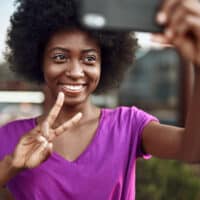 A black woman takes a selfie after stretching hair and styling her curls with coconut oil and coconut milk.