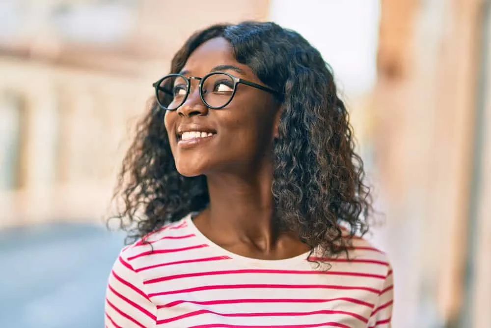 A cute black girl wearing an extra light hair-density wig with a natural and voluminous look.