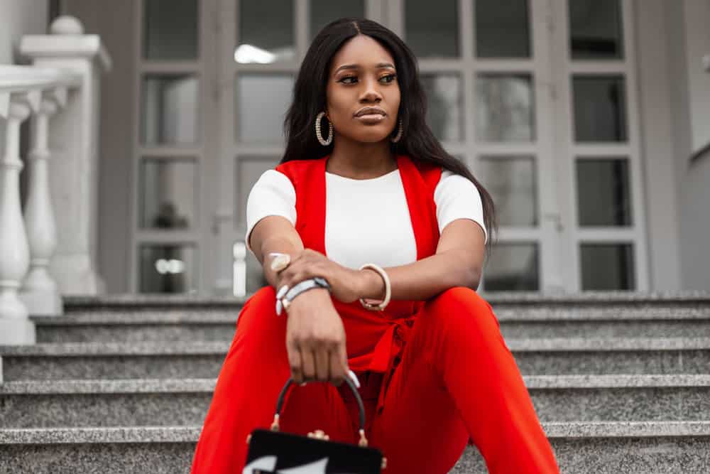 A young African woman is wearing a natural hairline lace front wig with mid-back wig length.