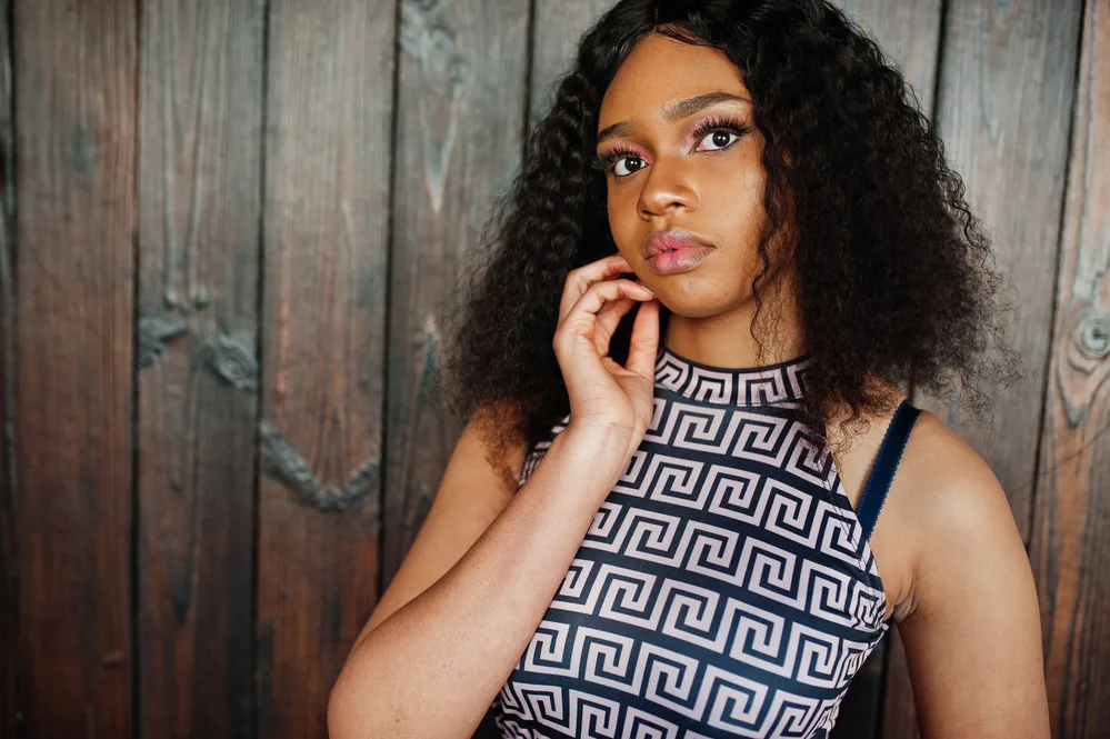 A black girl showcases a synthetic wig cap that creates a natural-looking hairline while also allowing for breathability and comfort.