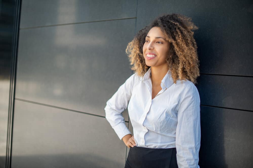 African American female with a beautiful smile washed her natural curls with an organic hair shampoo.