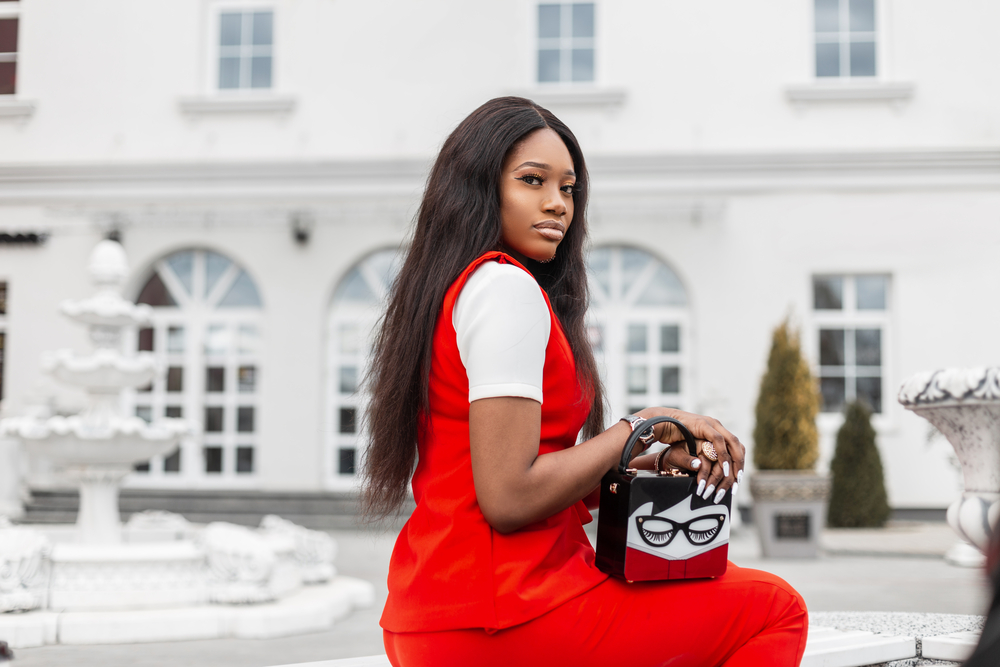 A beautiful black woman with a stylish handbag wearing a melted hairline HD wig.