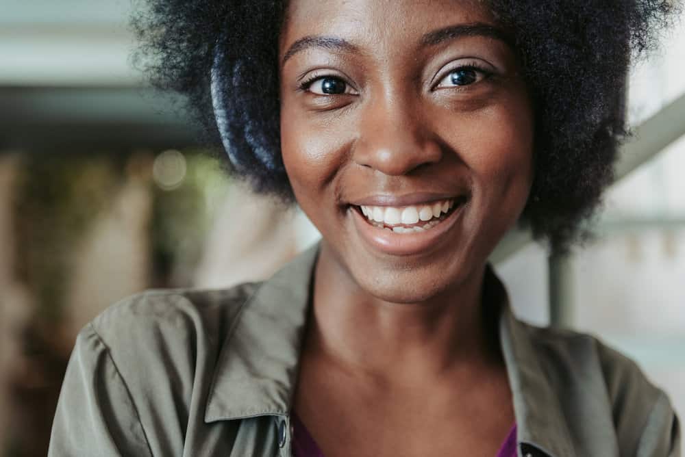 A cute African American female with kinky hair has tightly coiled strands styled with aloe vera gel.